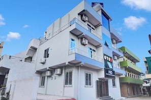 Un hôtel à plusieurs étages, doté de balcons, de climatiseurs et d’une enseigne indiquant « Hôtel OYO ».