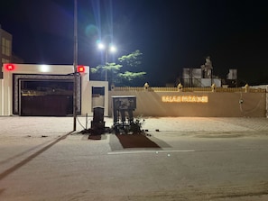 Ein begrenzter Eingang mit einem Neonzeichen für 'BALAJI PARADISE' und einer Statue im Hintergrund.