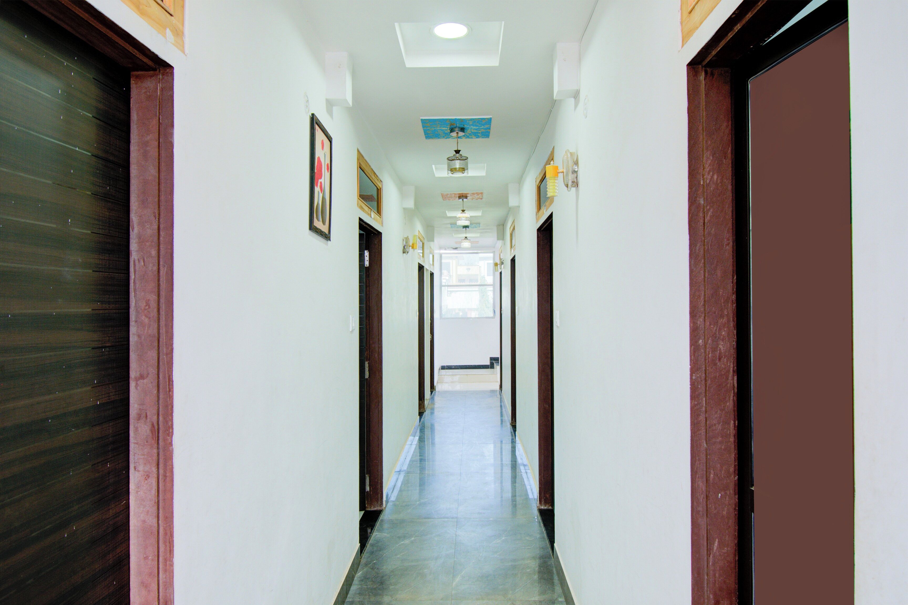 A hallway with doors on both sides, a tiled floor, and ceiling lights.