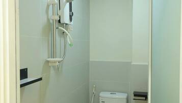 Baño pequeño y funcional con inodoro, ducha y secamanos.