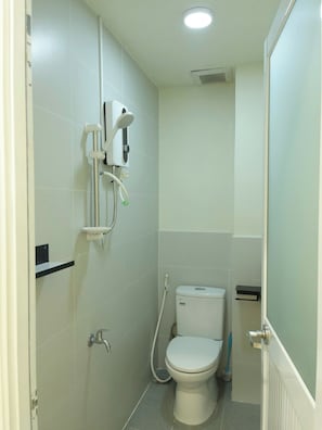 A small, compact bathroom with a toilet, a shower unit, and a hand dryer. - Haystay Sai Gon Dang Dung - Tan Dinh (Tan Dinh)