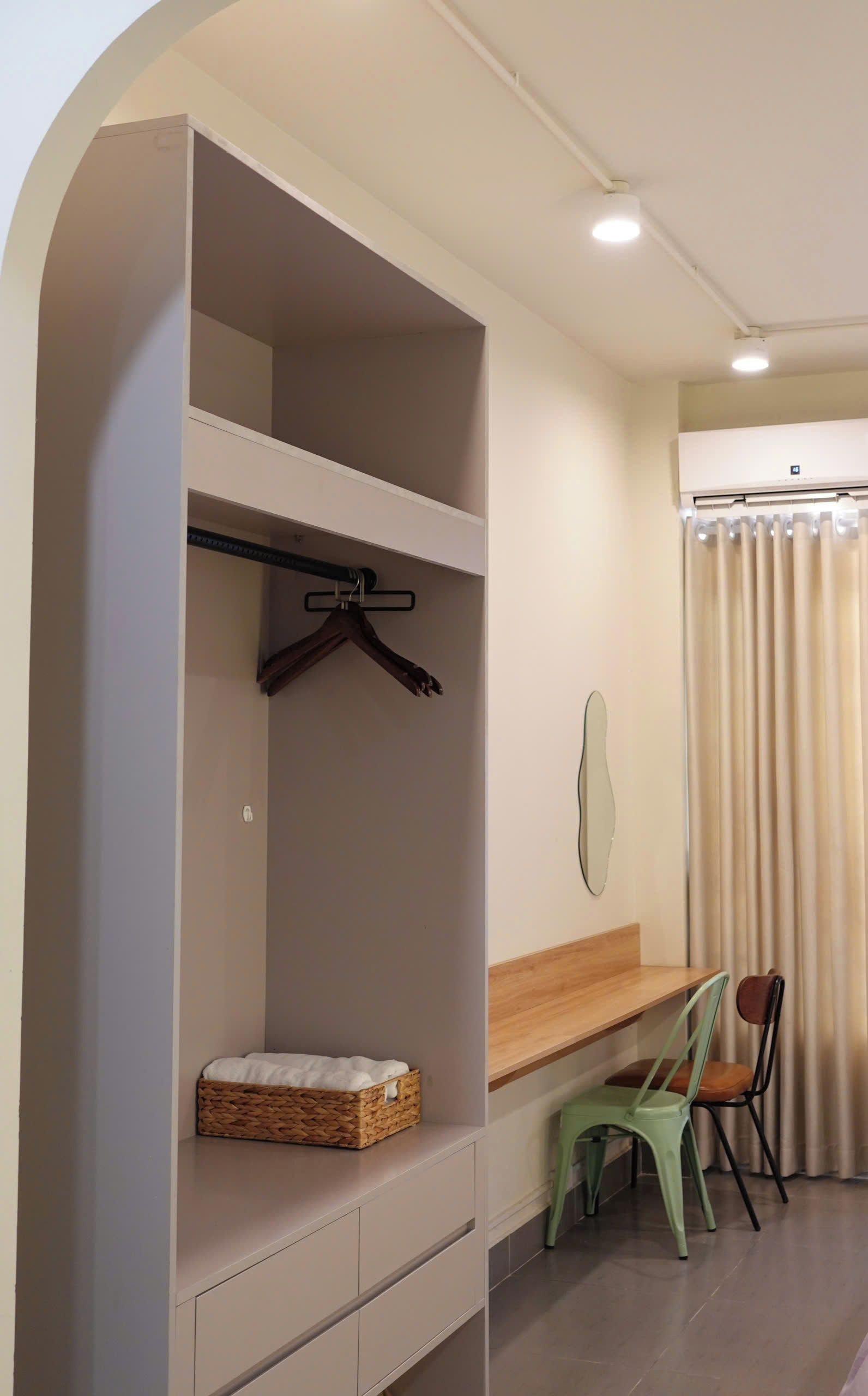 A room with a built-in wardrobe, a small table, two chairs, and a hanging mirror.