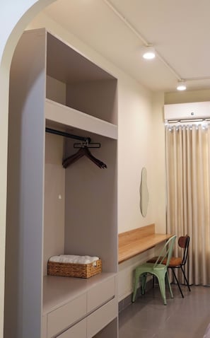 A room with a built-in wardrobe, a small table, two chairs, and a hanging mirror. - Haystay Sai Gon Dang Dung - Tan Dinh (Tan Dinh)