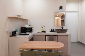 A compact kitchen with a microwave, sink, and a small dining area with two chairs. - Haystay Sai Gon Dang Dung - Tan Dinh (Tan Dinh)