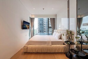 A modern hotel room with a large bed, a city view, a flat-screen TV, and a small table with decorative plants. - The MetropoIe Urban Residence Sai Gon  (An Khanh)