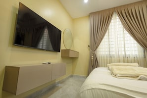 Une chambre d’hôtel équipée d’une télévision à écran plat, d’une table de chevet, d’un lit avec du linge de lit blanc et d’une fenêtre avec des rideaux.