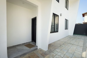 Un bâtiment doté d’une terrasse carrelée, d’une porte et d’une fenêtre.