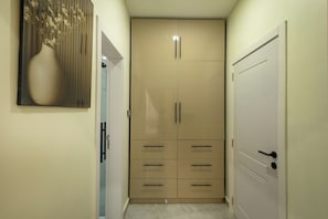 Un couloir avec une armoire beige, une porte dotée d’une poignée et un tableau encadré accroché au mur.