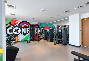 Una palestra con attrezzature per l'allenamento e un murale colorato al muro.