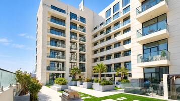 Un edificio residenziale a più piani con balconi, posti a sedere all'aperto e un cortile curato.