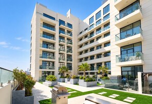 Un edificio residenziale a più piani con balconi, posti a sedere all'aperto e un cortile curato.