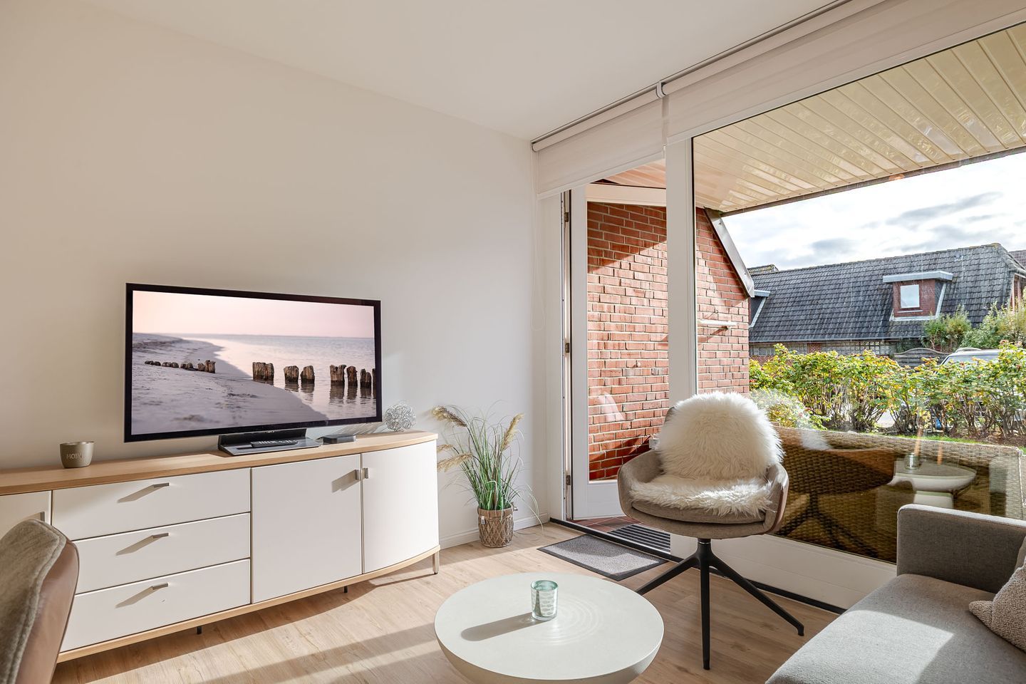 Un salon moderne comprenant un téléviseur, un canapé, un fauteuil et une petite table.