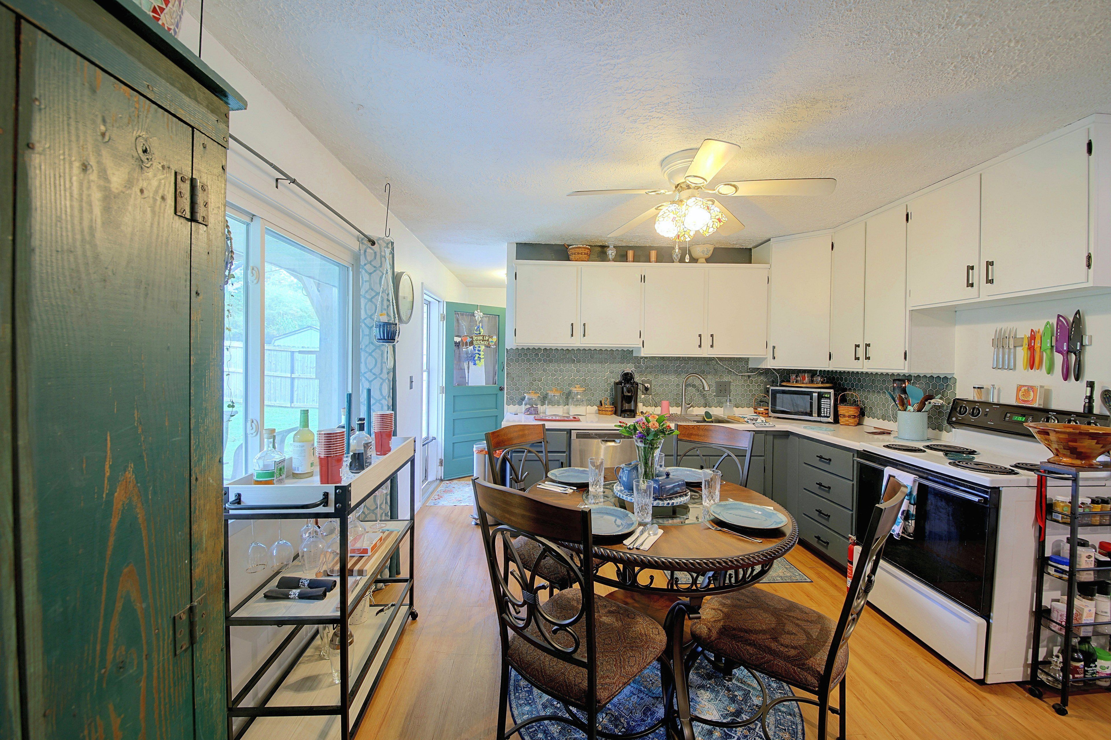 A kitchen with a dining area, a ceiling fan, and a view through a window.
