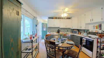A kitchen with a dining area, a ceiling fan, and a view through a window.
