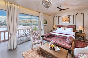 Una habitación de hotel con cama, sofá, mesa de centro y vistas a un paisaje natural.