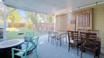 An outdoor patio area with a covered seating arrangement, a wooden fence, and a signboard.