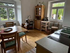 Eine gut beleuchtete Küche mit Holzausstattung, einem Esstisch, Stühlen und einer Arbeitsplatte.