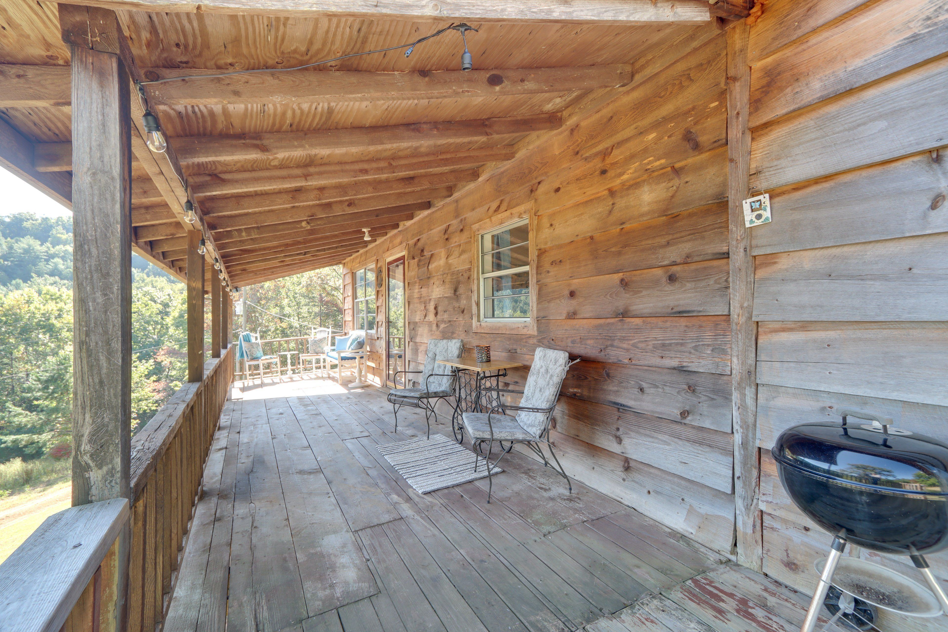 Eine Holzhütte mit Veranda, Sitzgelegenheiten im Freien und Grill.