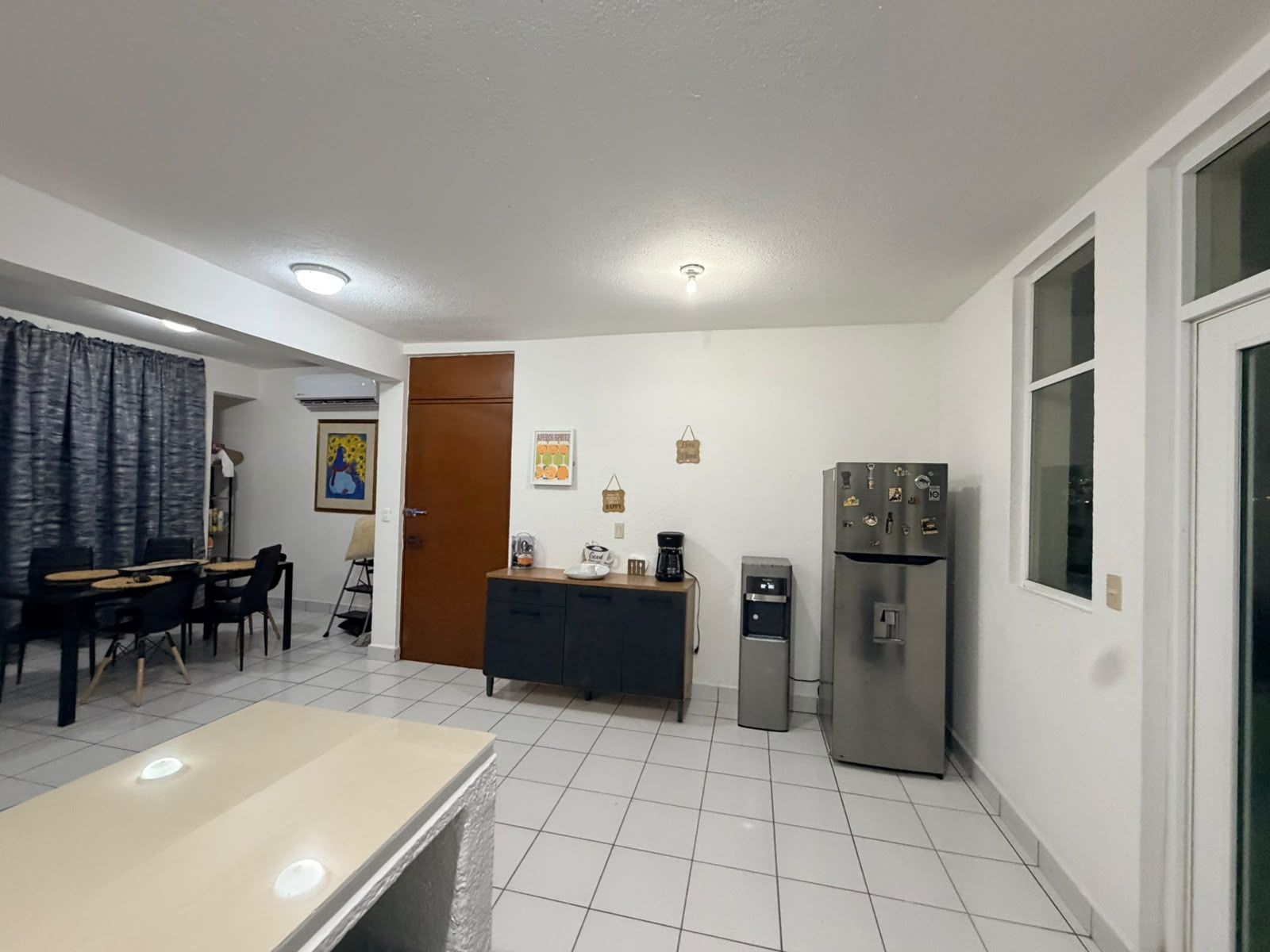 A compact kitchen with a refrigerator, a coffee maker, and a small cabinet.