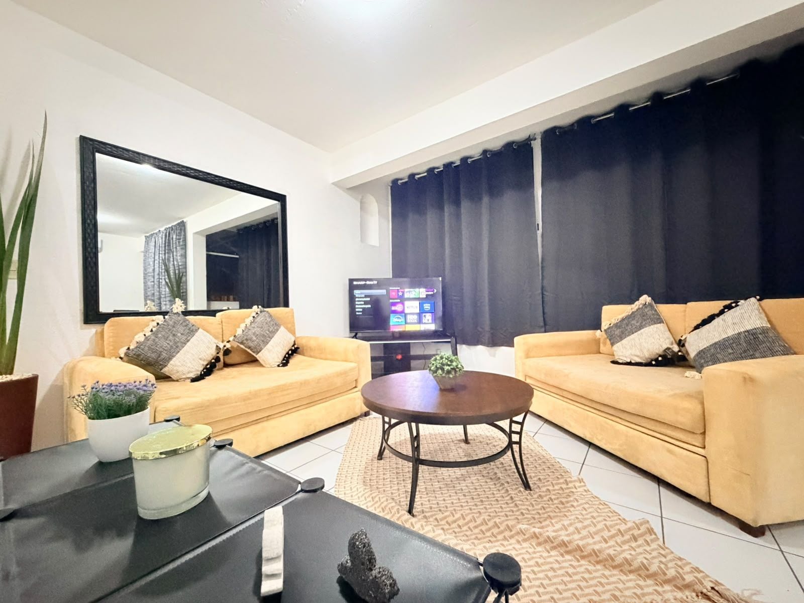 A modern living room with two sofas, a coffee table, a TV, and a large mirror.