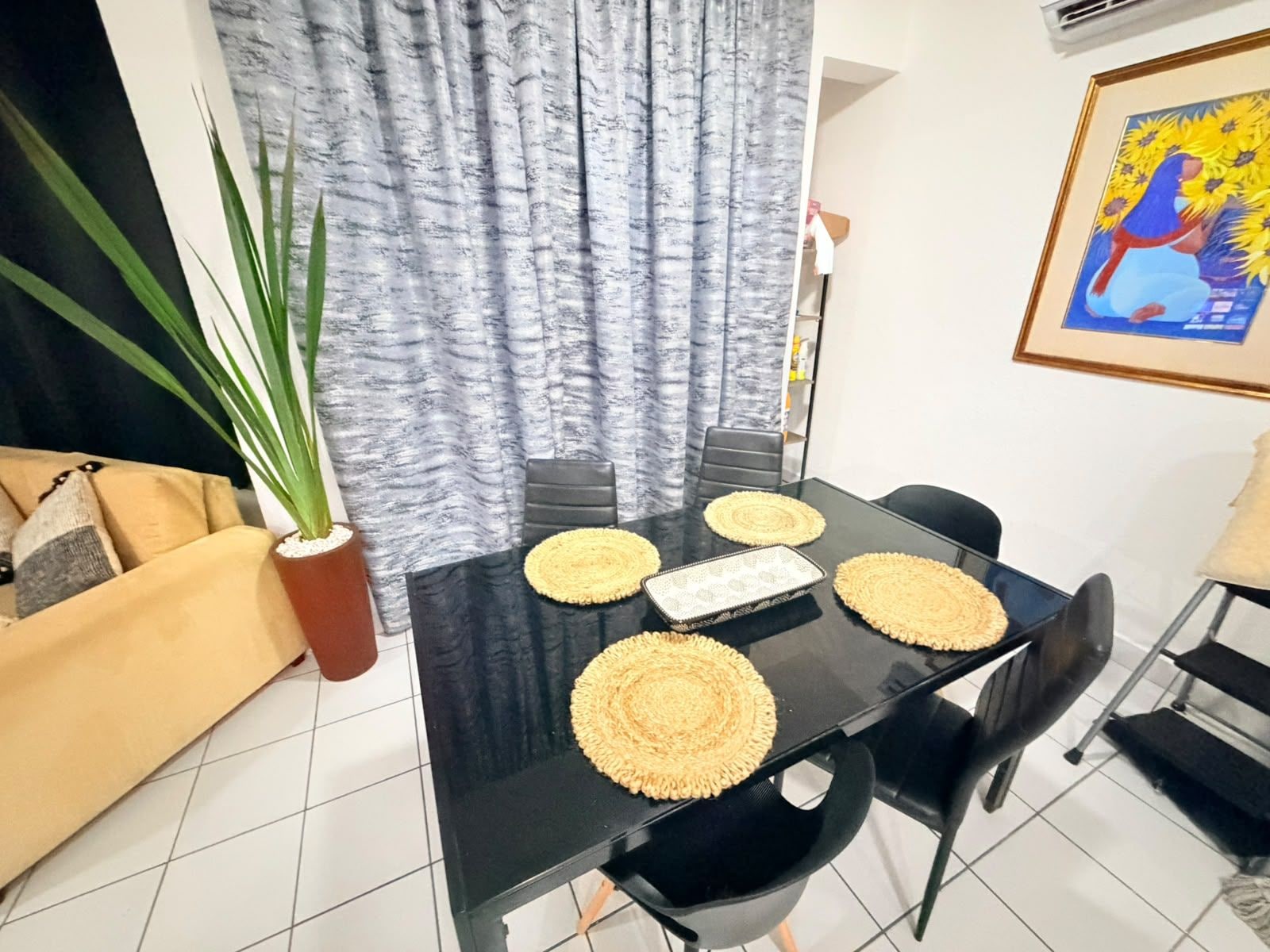A dining area with a black table, four chairs, and woven placemats.