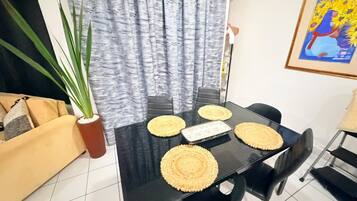 A dining area with a black table, four chairs, and woven placemats.