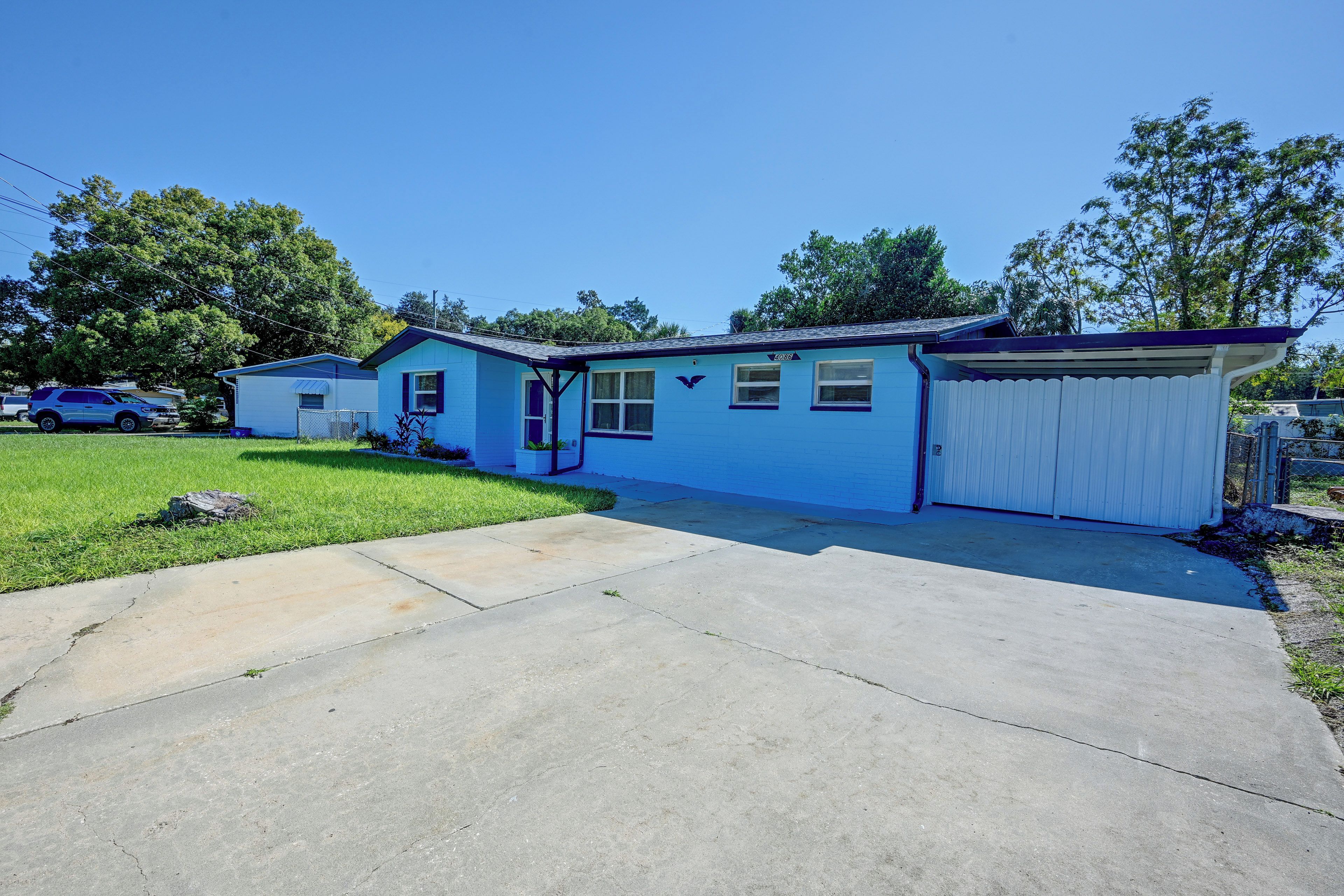 A single-story residential building with a blue exterior, a garage, and a driveway.