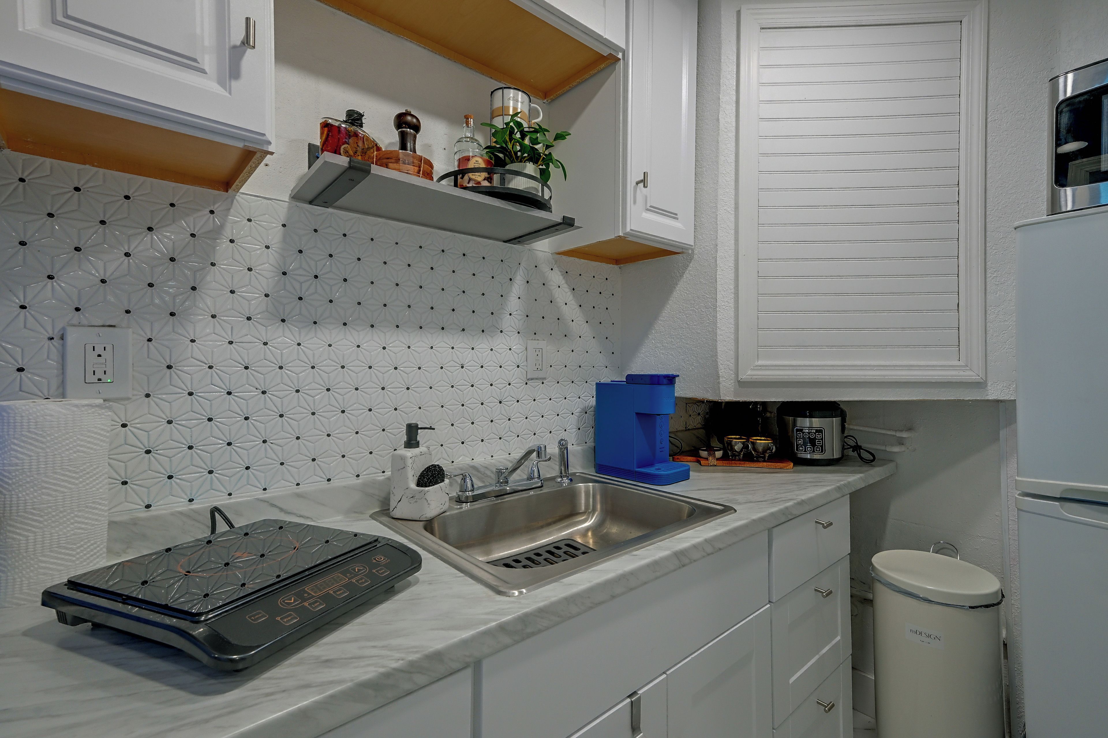 A modern kitchen with a built-in oven, a sink, and a coffee maker.