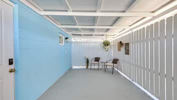 Um corredor com uma parede azul de um lado e uma parede branca do outro, que leva a um espaço de estar com duas cadeiras e uma mesa.