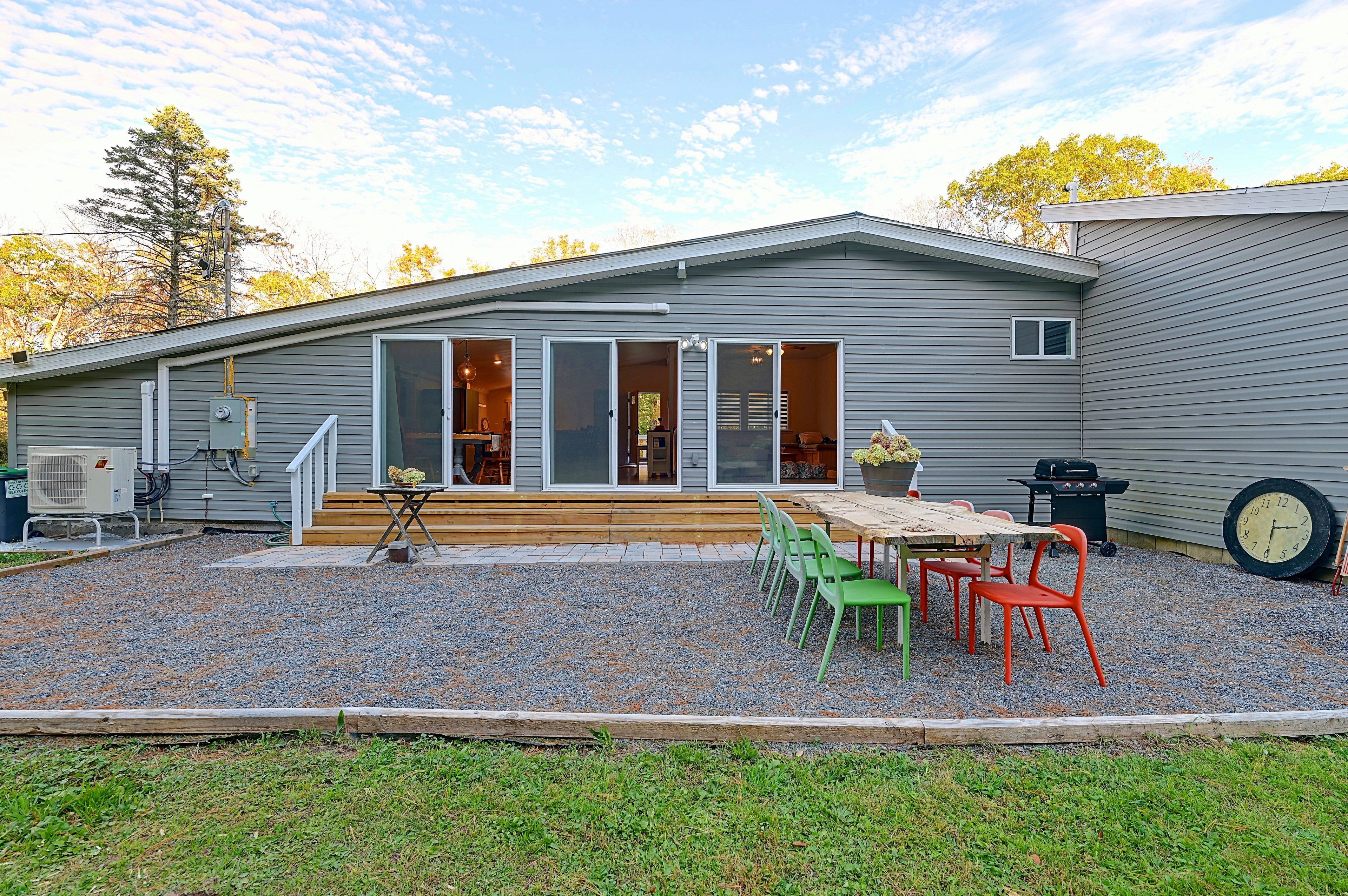 A single-story house with a patio area, outdoor seating, and a grill.