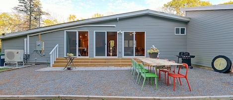 A single-story house with a patio area, outdoor seating, and a grill.