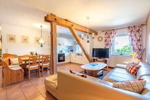 Ein gemütliches Wohnzimmer mit einer Couch, einem Esstisch mit Stühlen, einer Küchenzeile und einem Fernseher.