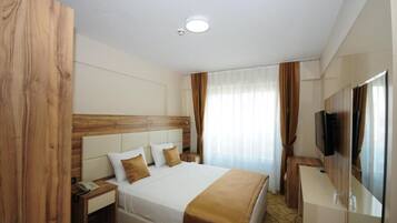 A hotel room with a bed, bedside table, and a TV mounted on the wall.