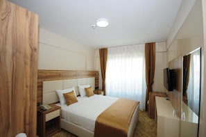 Ein Hotelzimmer mit Bett, Nachttisch und an der Wand montiertem Fernseher.