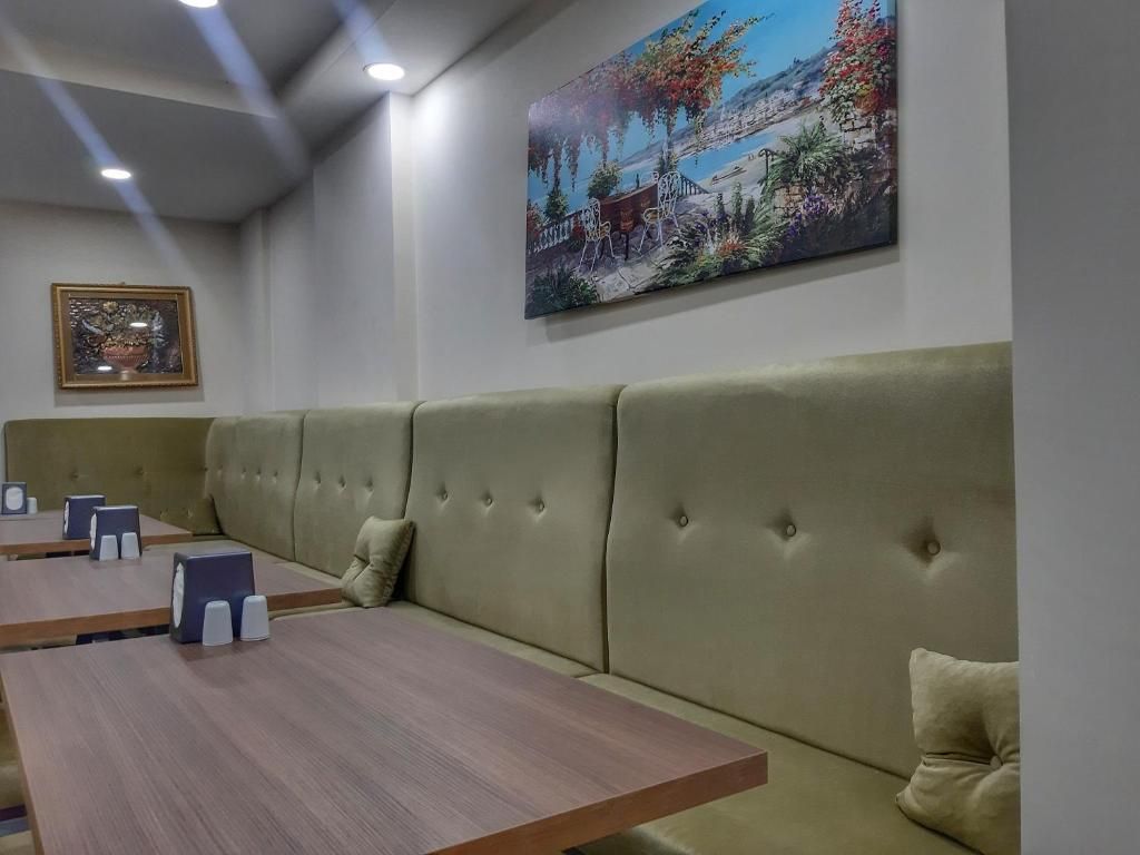 A seating area with a sofa and tables, a painting on the wall, and a framed picture.