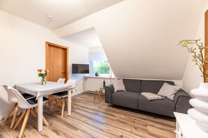 Ein stilvolles Wohnzimmer mit Essbereich, einer Couch und einem Fernseher.