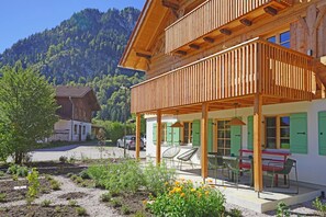 Eine Holzhütte mit Balkon, Sitzgelegenheit im Freien und einem Garten.