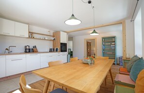 Eine moderne Küche mit weißen Schränken, einem Holztisch und einer grünen Pendelleuchte.