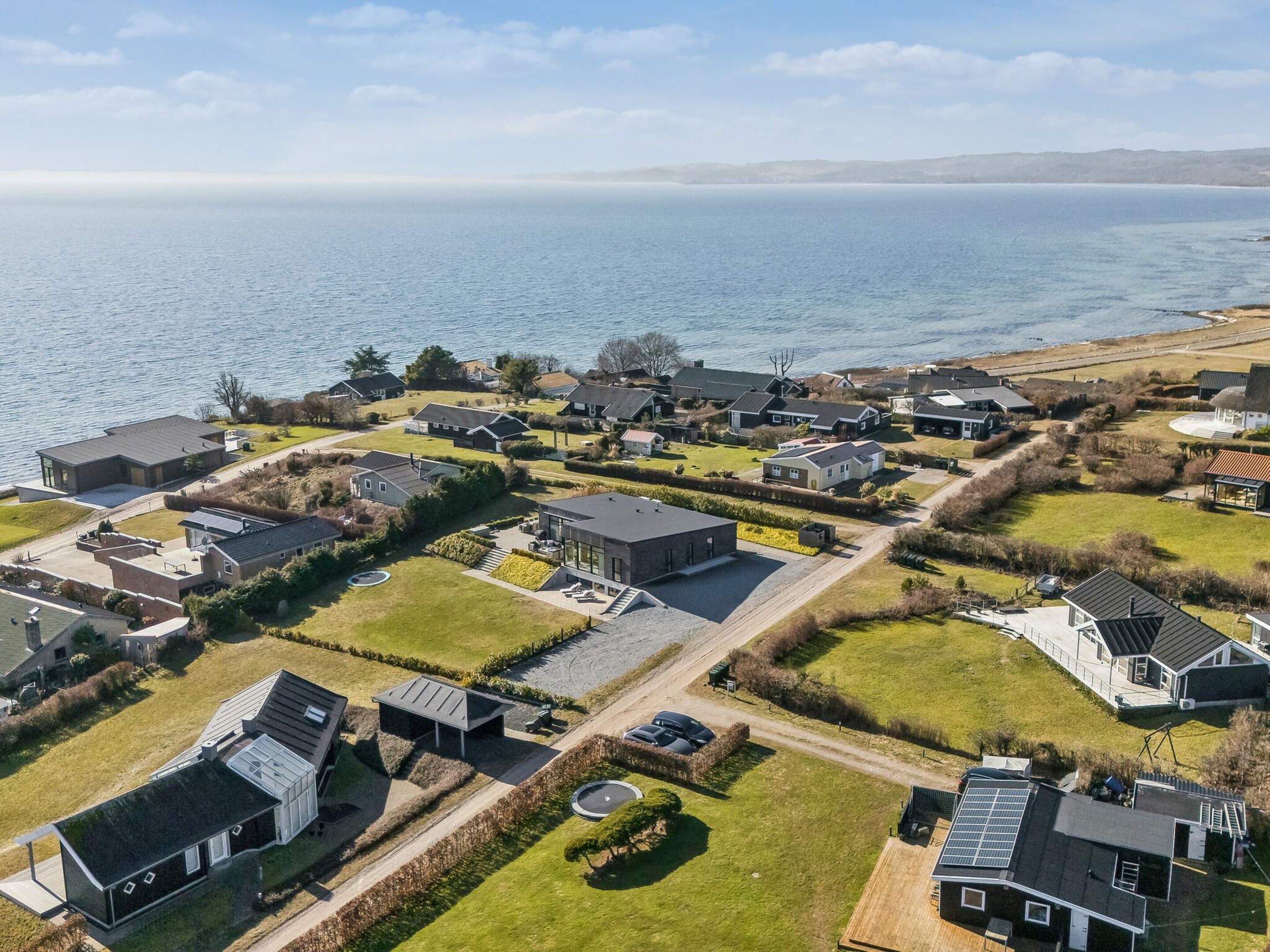 A residential area with houses, a road, and a body of water in the background.