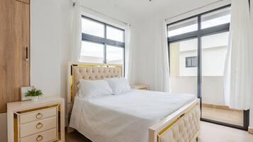 Een slaapkamer met een bed, nachtkastjes, een garderobe en grote ramen.