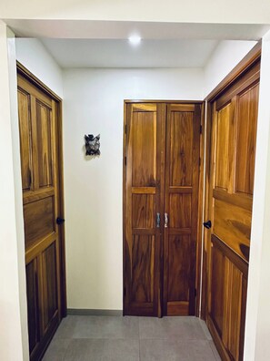 Une pièce d’angle avec deux portes en bois, un petit élément décoratif mural et un sol carrelé.