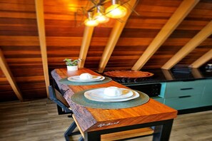 Ein Holztisch mit zwei Tellern und einer Tasse, vor einer schrägen Decke mit freiliegenden Balken.