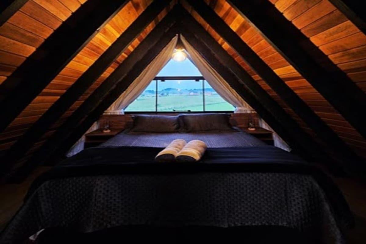 Ein schrägwandiges Schlafzimmer im Dachgeschoss mit einem Bett, einem Fenster und einem Nachttisch.