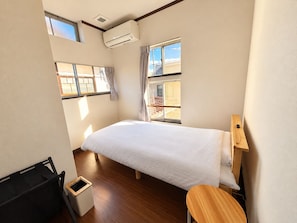 A bedroom with a bed, a window, a small table, and a trash bin. - KUROKOCHI STAY (Nakamachi, Aizuwakamatsu-shi)