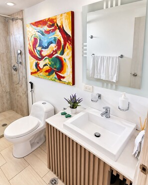 A modern bathroom with a shower, toilet, sink, and a large abstract painting. - New Listing (Cartagena de Indias)