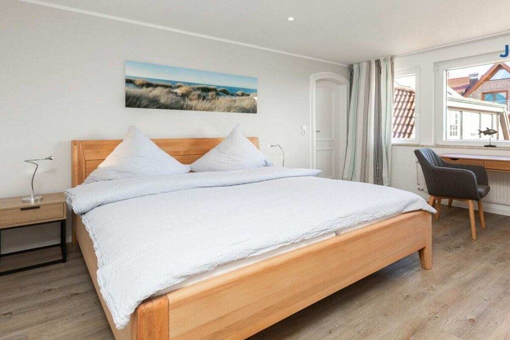 Een slaapkamer met een houten bed, een bureau en een stoel.
