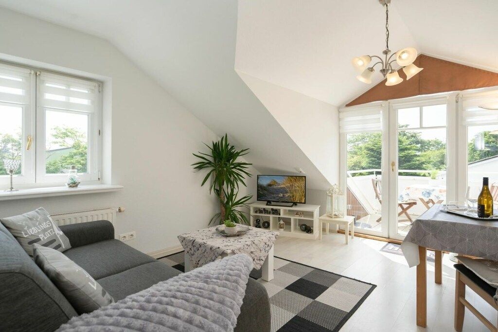 Uma sala de estar moderna com um sofá, uma mesinha, uma televisão e um espaço de refeições com mesa e cadeiras.
