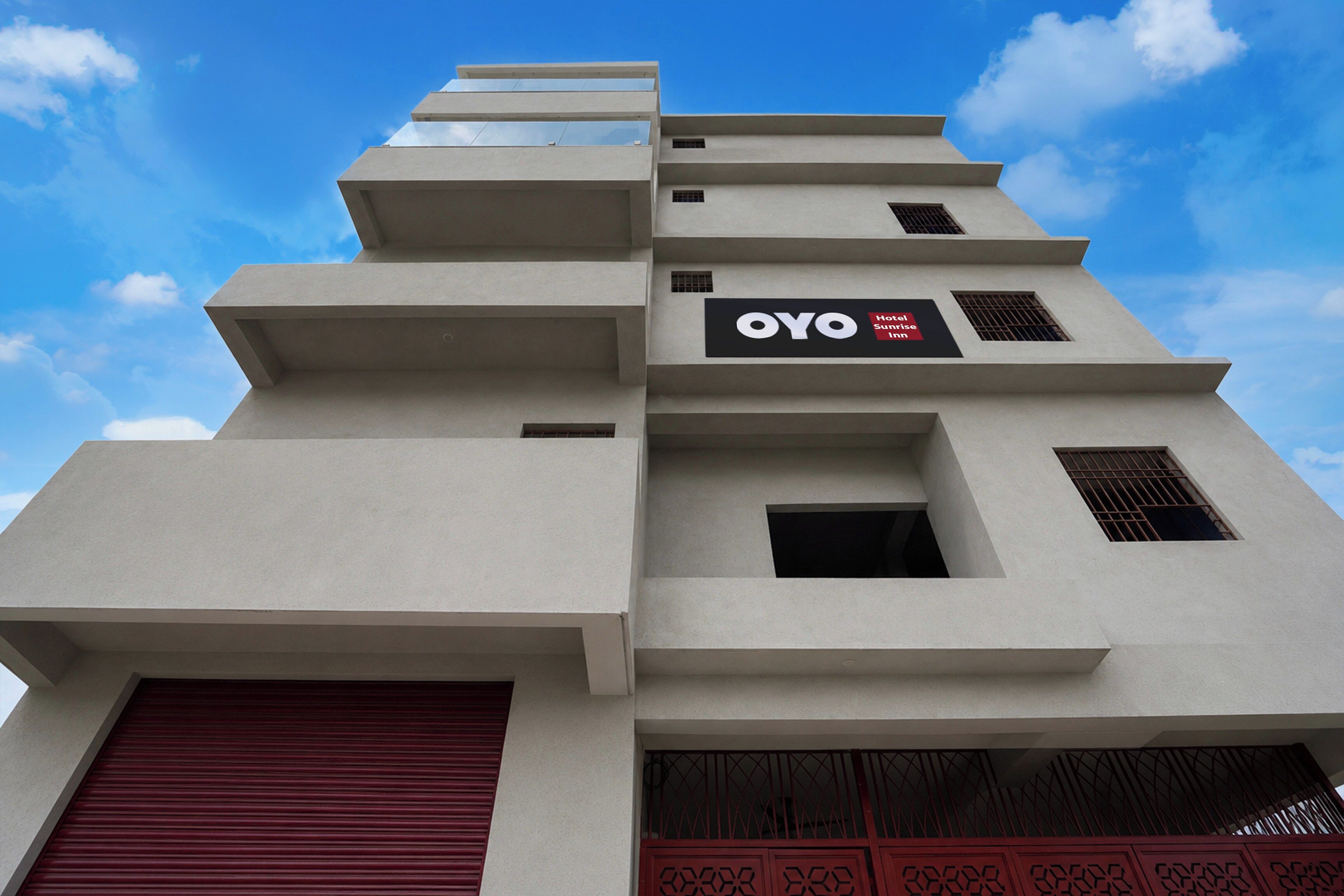 A modern building with a flat facade, multiple levels, and a prominent OYO Hotel Sunrise Inn sign.