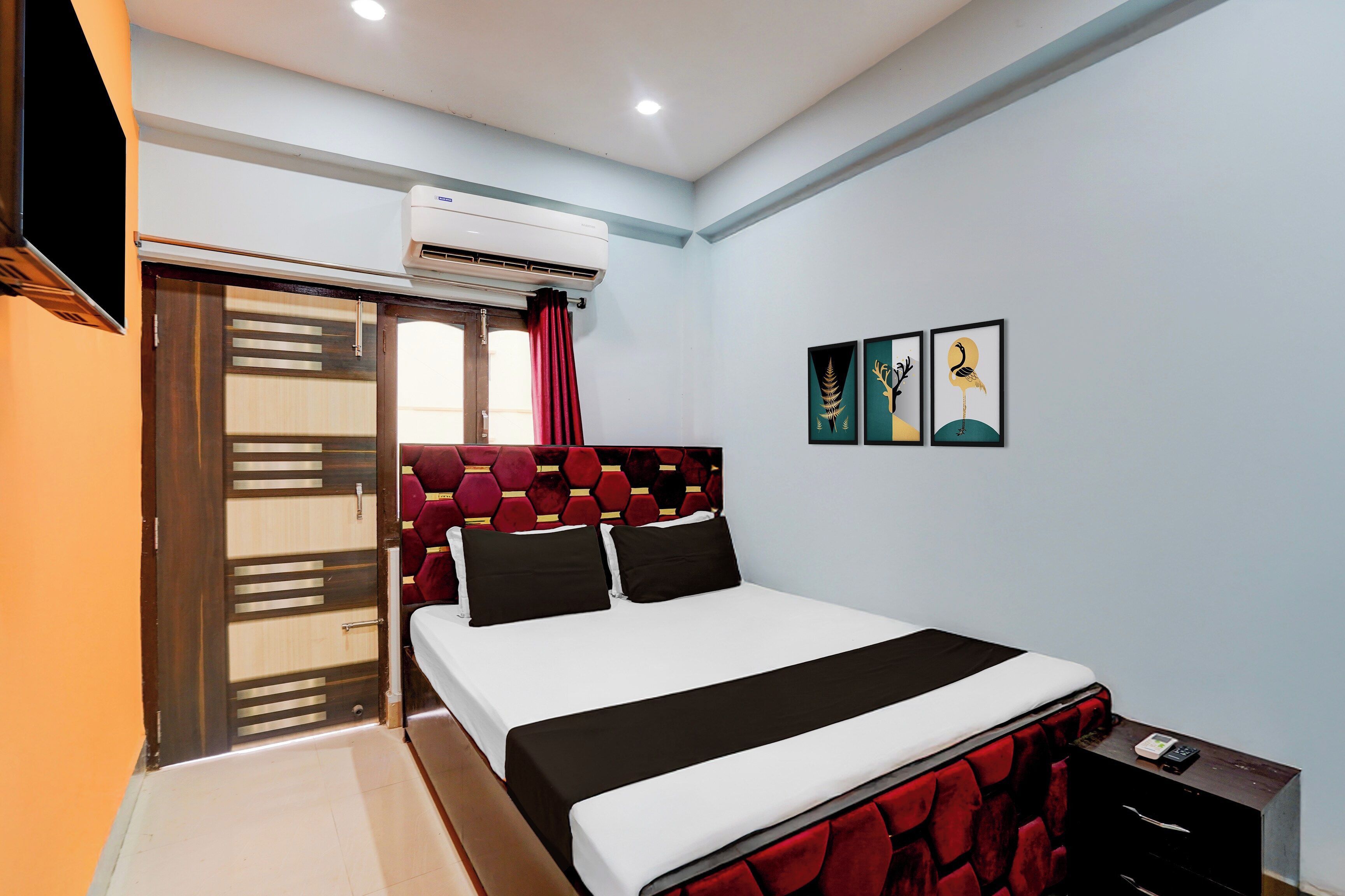 Un dormitorio con cama, aire acondicionado, una puerta corredera y obras de arte en la pared.