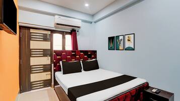 Un dormitorio con cama, aire acondicionado, una puerta corredera y obras de arte en la pared.